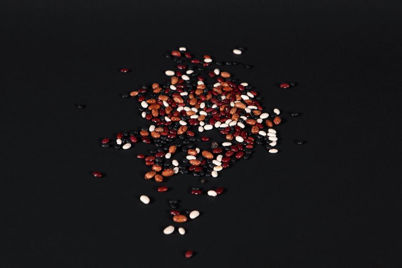 Des f&egrave;ves rouges, blanches, noires et jaunes sont m&eacute;lang&eacute;es ensemble.